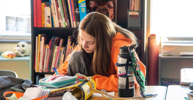 Female student working at a desk with books and a water bottle