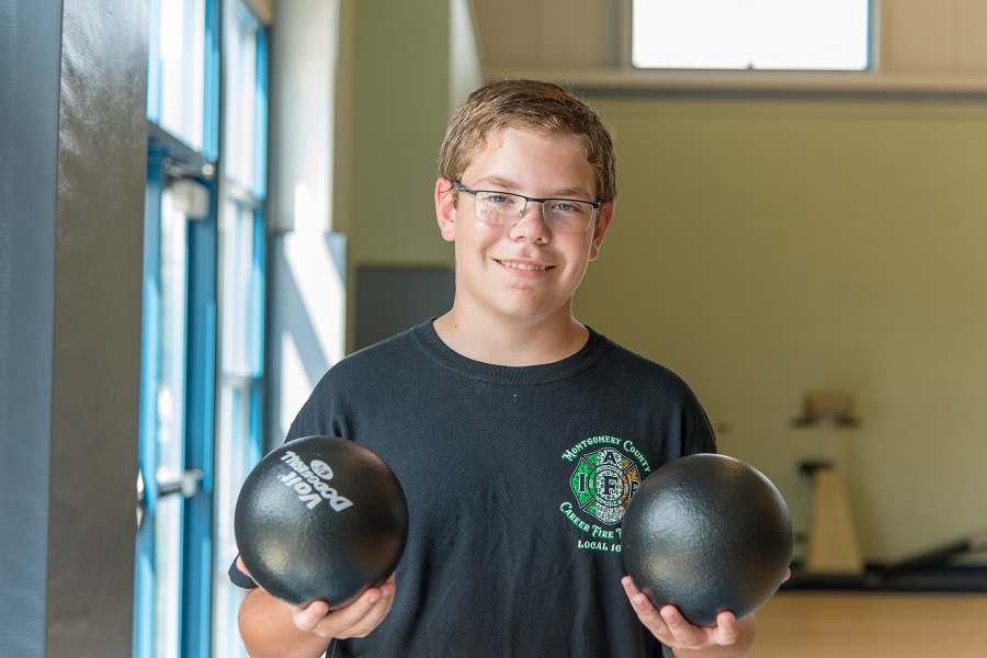 Mick F. Child smiling, holding two small bowling balls