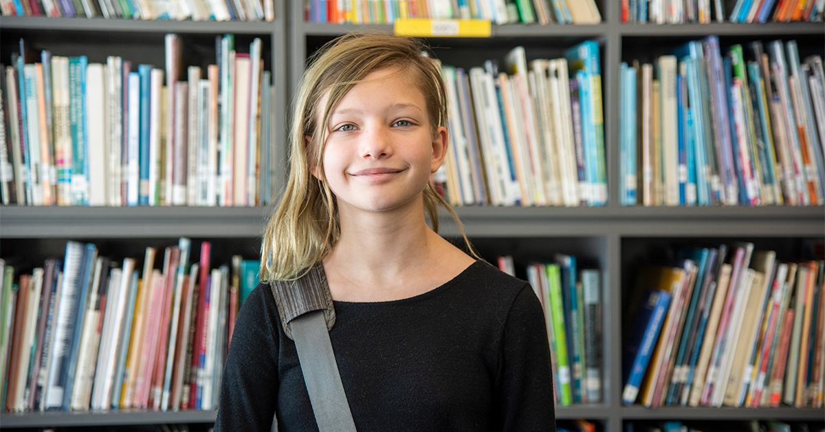 young student in front of books smiling