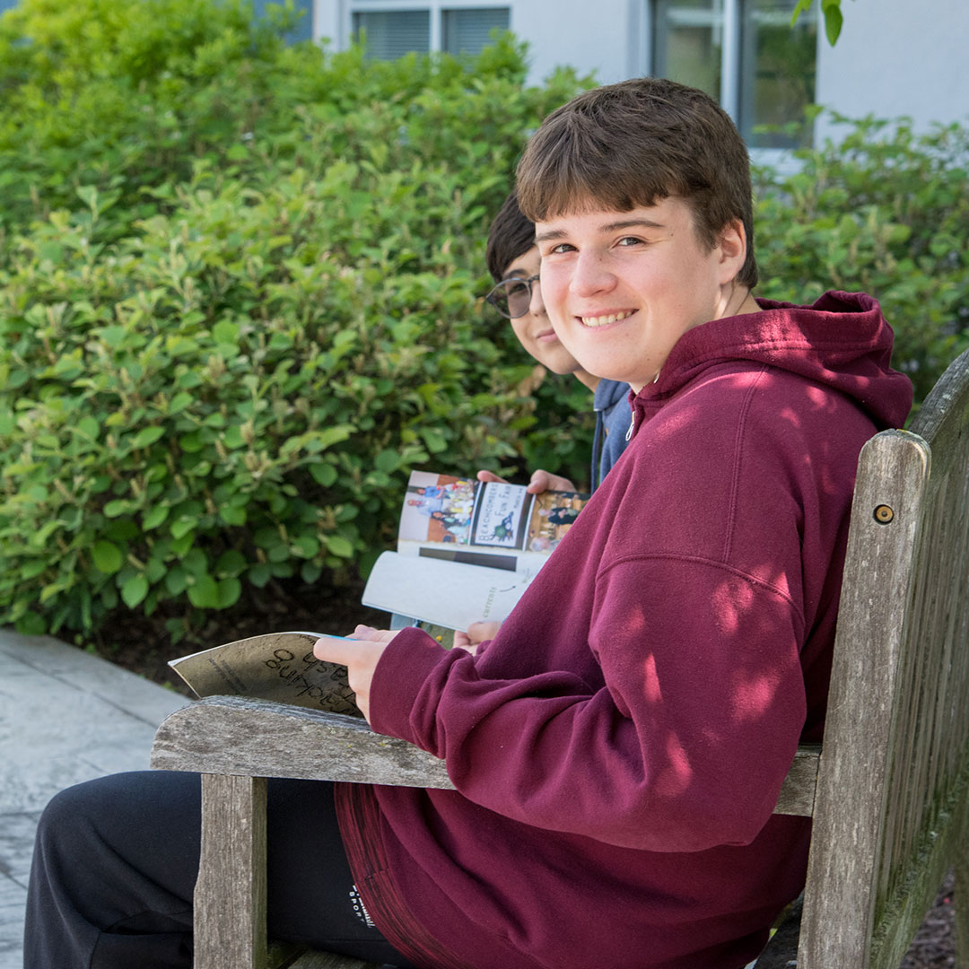 young-boy-sitting-on-bench-and-reading-a-book