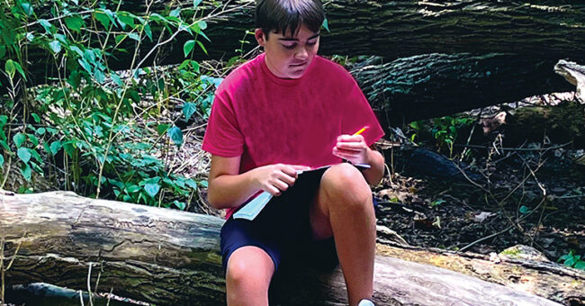 Young male student learning outdoors.