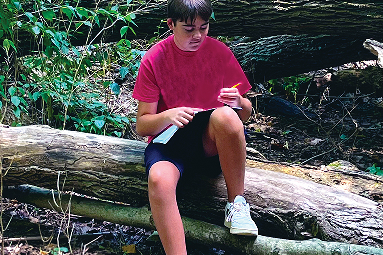 Young male student learning outdoors.