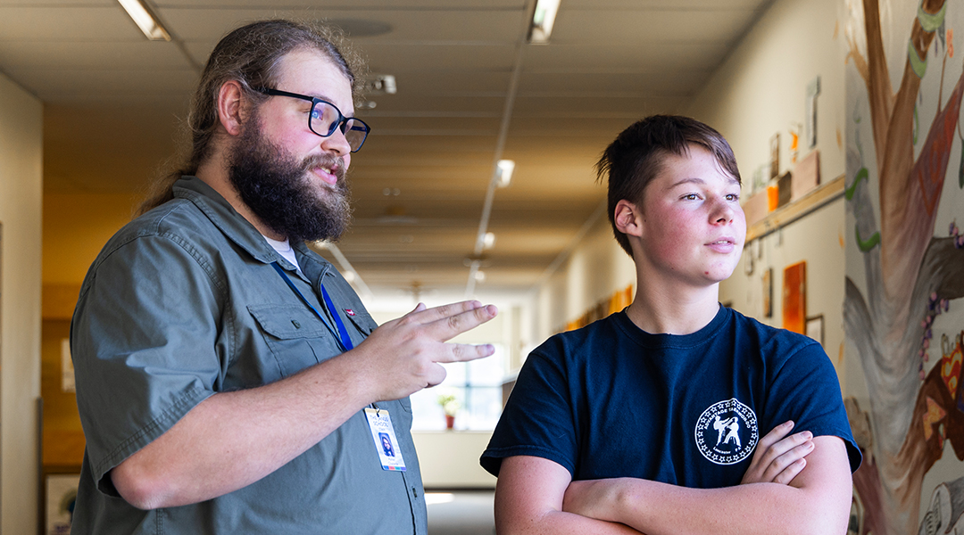 Teacher and male student standing in a hallway