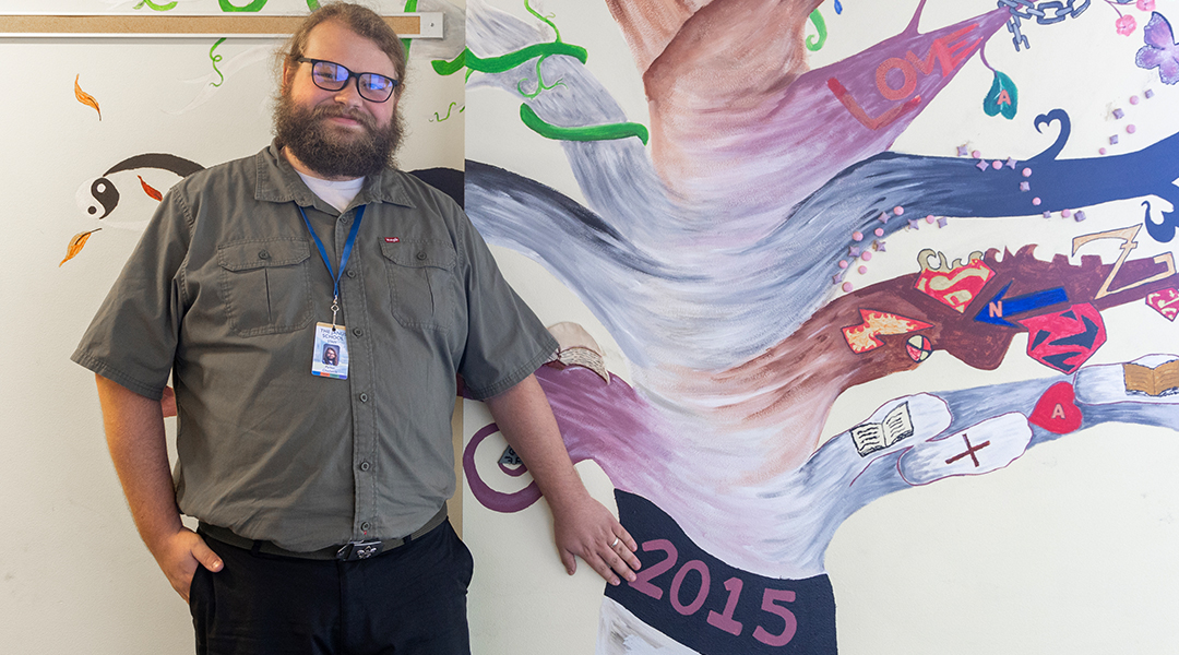 Teacher standing in front of a purple tree mural