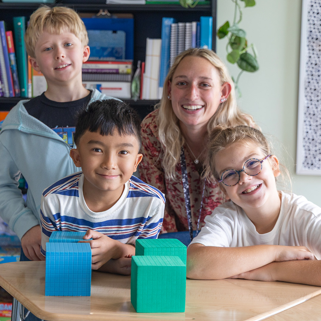 Group of students sitting at desk with their teacher